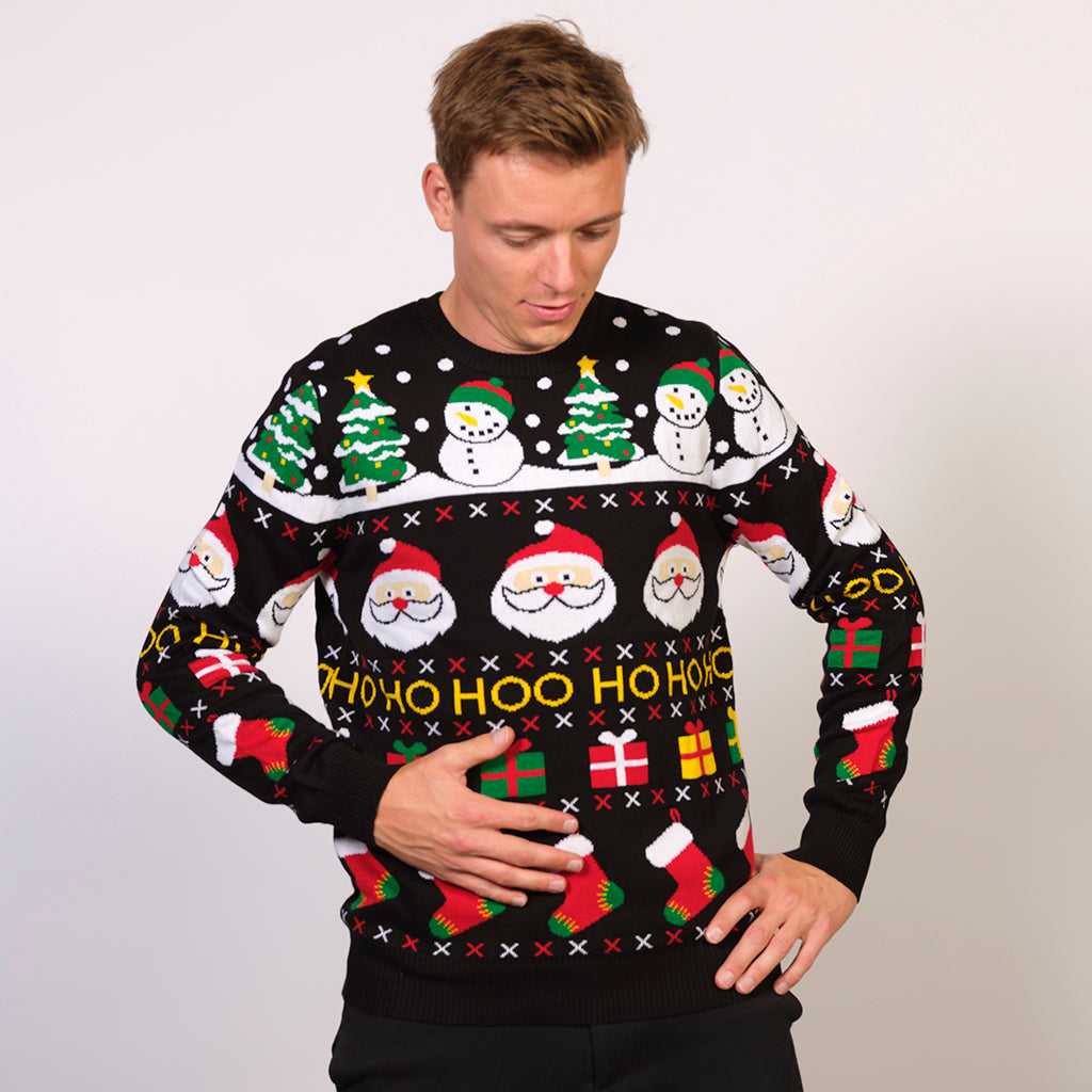 Ein Mann trägt einen schwarzen Weihnachtspulli mit Weihnachtsmotiv.